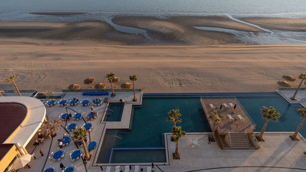 Ein Resort mit Pool, Liegebereich und Blick auf den Strand.
