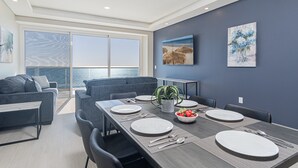 Un comedor moderno con una mesa grande dispuesta para seis personas, un sofá y vista al mar.