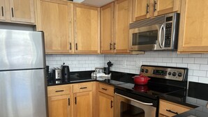 Une cuisine avec des meubles en bois, un réfrigérateur en acier inoxydable, un four à micro-ondes, une cuisinière et un évier.
