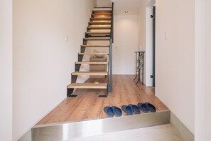 A modern staircase with wooden steps and metal railings, leading to a landing area with a sink and a shelf with toiletries. - Villa Kanasa YUKUI (Onna)