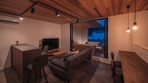 Ein moderner Wohnbereich mit Holzboden, einem Fernseher, einer Couch und einem Essbereich.