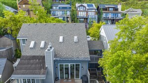 A modern two-story house with a large deck, multiple windows, and a chimney. - 3BR home central to Main Street and hiking trails, with private firepit, hot tub & balcony (Park City)