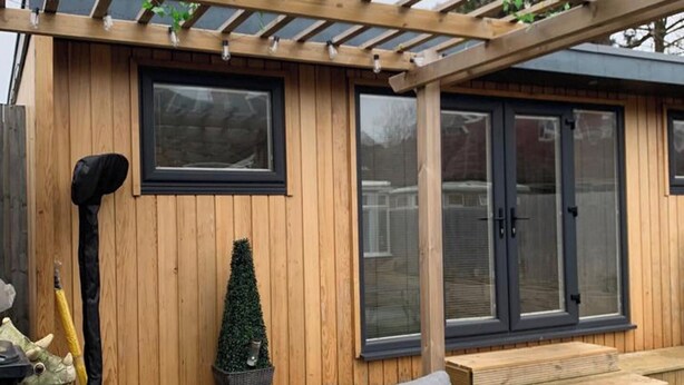 A wooden house with a patio, a small garden, and a grey sofa. - Lodge Sleeps 2 with Free Parking (Hove)