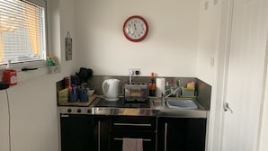 A compact kitchen with a stainless steel countertop, a kettle, a toaster, and a sink. - Lodge Sleeps 2 with Free Parking (Hove)