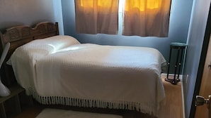 Una camera da letto con un letto di legno, una coperta bianca e un piccolo tappeto.