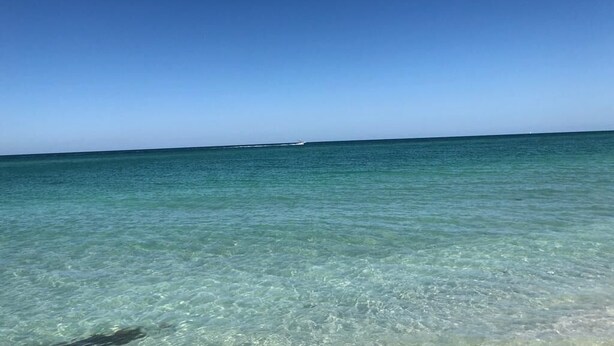 A clear view of the ocean with a boat in the distance.