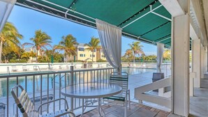 A covered outdoor seating area with a pool, chairs, and a table.