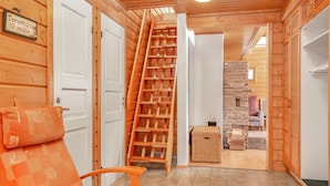 A wooden interior with a chair, a ladder, and a sign indicating a room number.