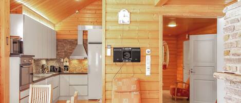 A modern kitchen with built-in appliances, a dining area with wooden furniture, and a stone wall.