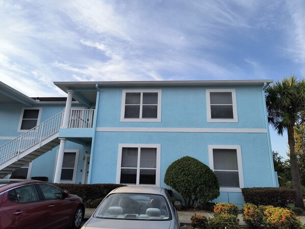 A two-story building with a blue exterior, a white staircase, and a small balcony.