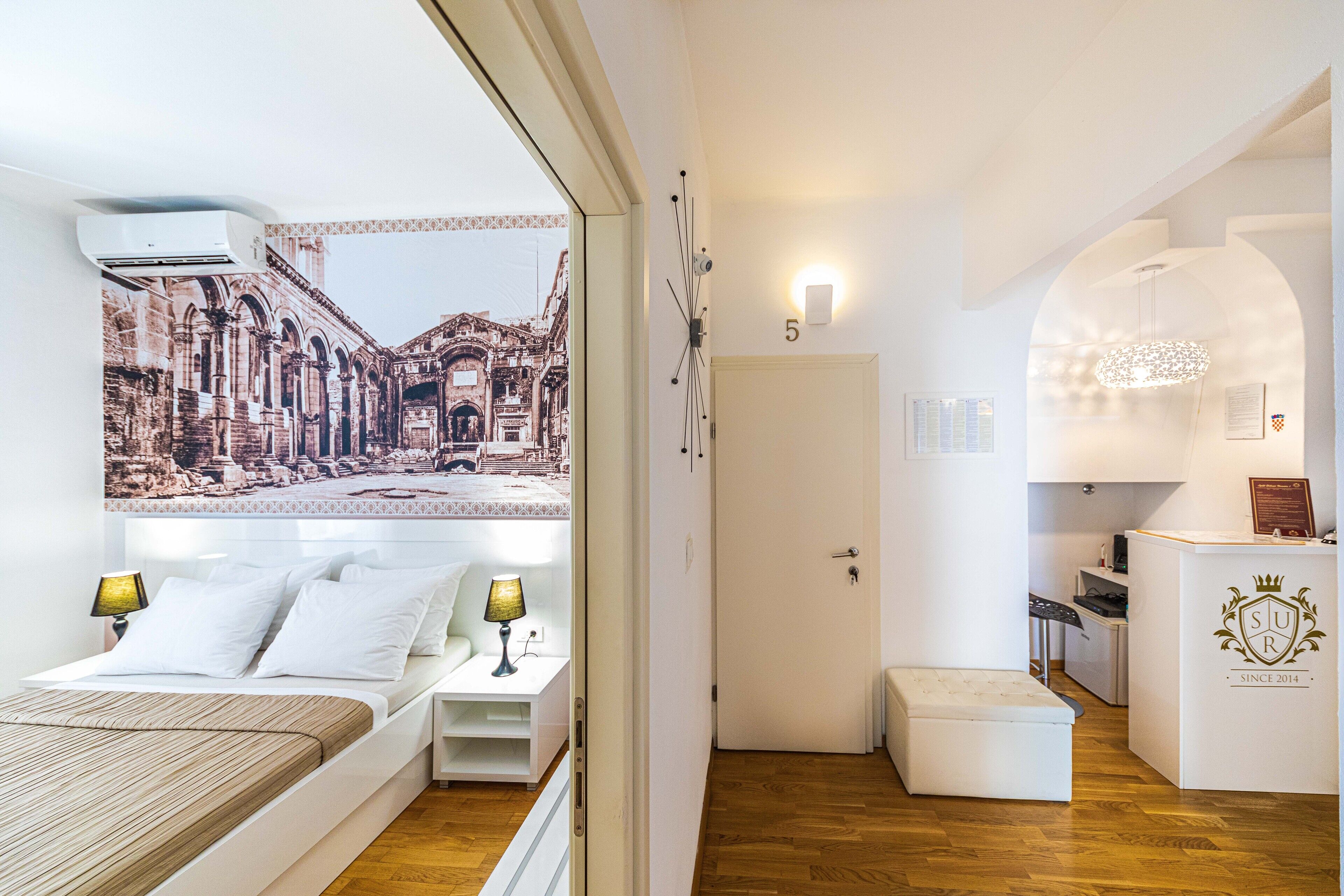 Une chambre d’hôtel avec un lit, des tables de chevet, un bureau et une vue sur le paysage urbain par la fenêtre.