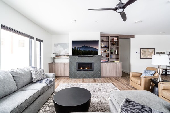 Una sala de estar moderna con chimenea, un sofá, una mesa de centro y una estantería.