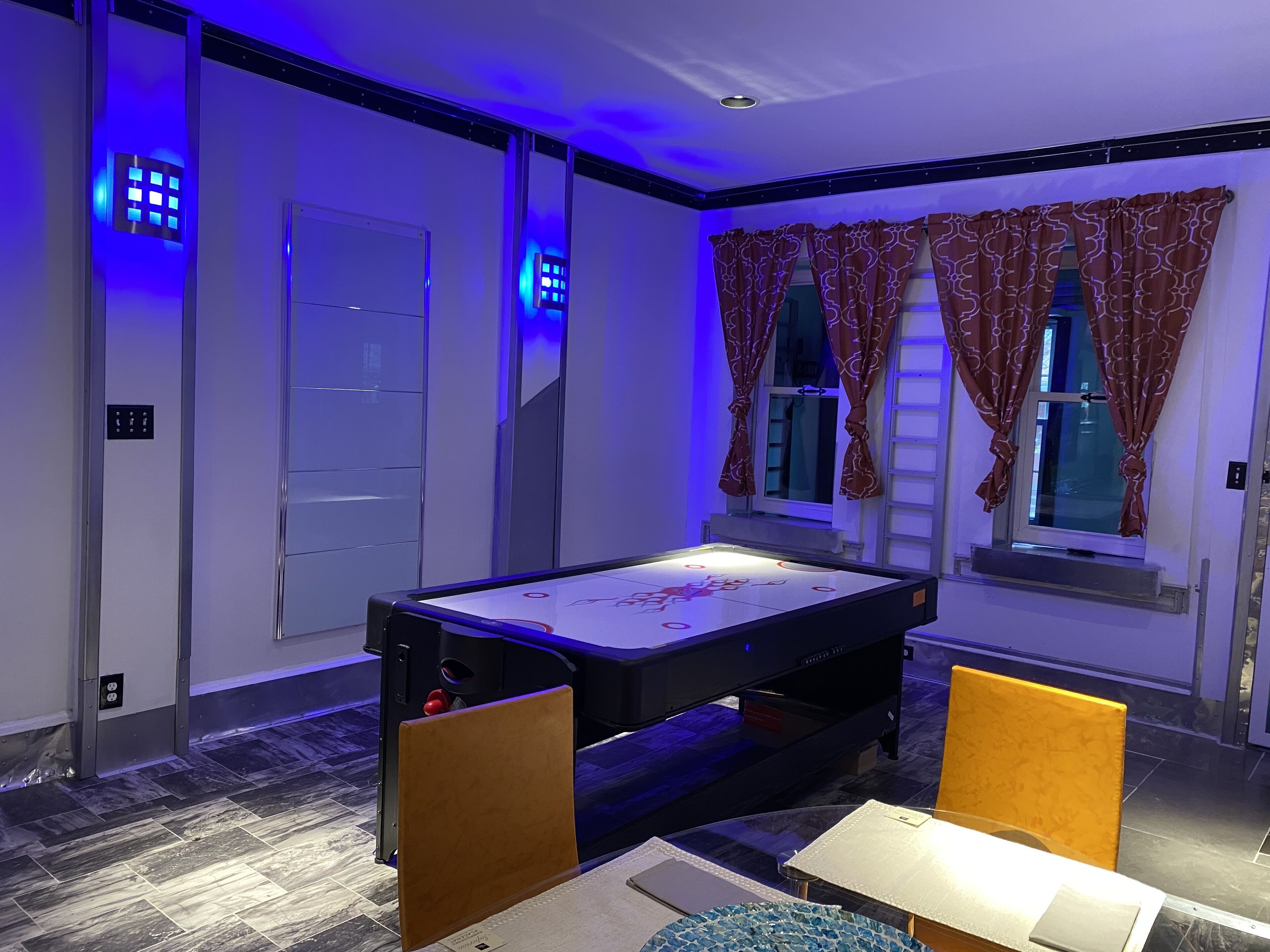 A billiards table in a room with a window, curtains, and a door.