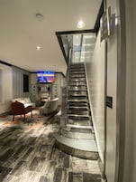 Una sala de estar moderna con una escalera curva, un televisor de pantalla plana y un sofá.