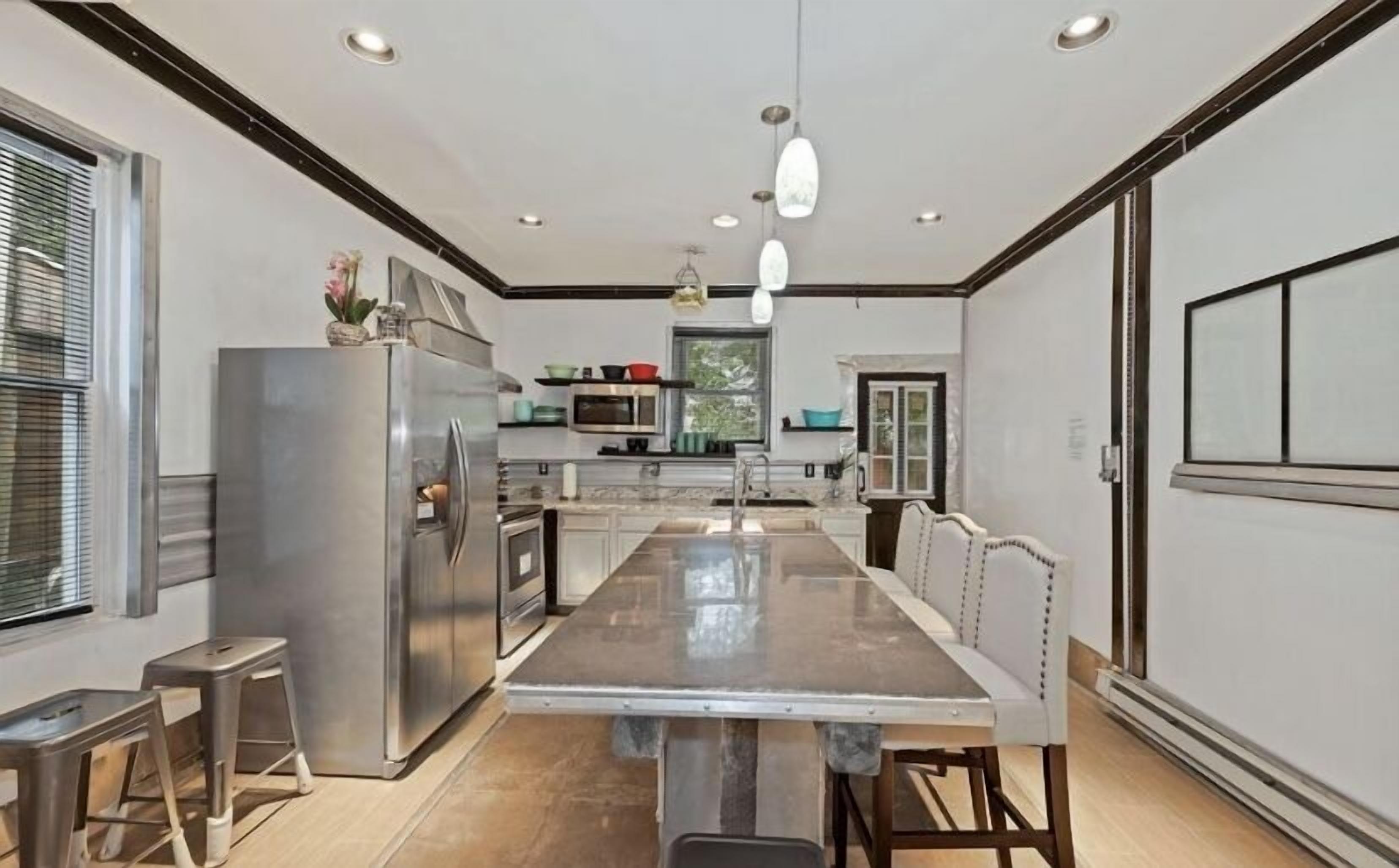 A modern kitchen with stainless steel appliances, a central island, and pendant lighting.