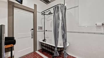 A bathroom with a shower, white tiled walls, a door, and a tiled floor.