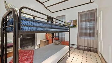A bunk bed with a patterned mattress, a red blanket, and a small table with a chair.