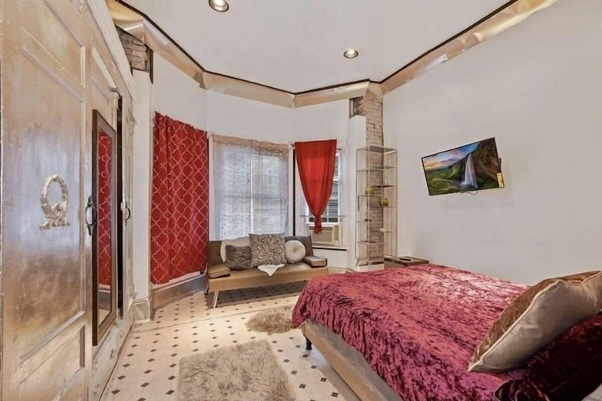 Une chambre à coucher avec un lit, une armoire, une fenêtre avec des rideaux, un tableau au mur et un tapis sur le sol.