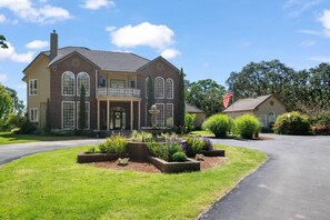 A two-story house with a front porch, a fountain, and a flag.