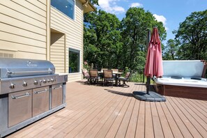 A deck with a barbecue grill, a hot tub, and a table with chairs.