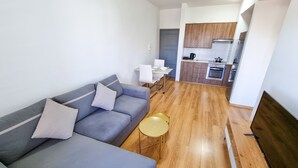A modern living room with a grey sofa, a small round table, and a kitchen in the background. - Springfield Park Apartment (Larnaca)