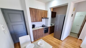 A modern kitchen with wooden cabinets, a stainless steel refrigerator, and a dining area with a table set for four. - Springfield Park Apartment (Larnaca)