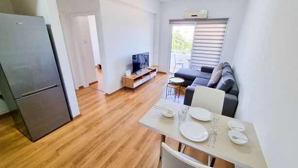 A compact living space with a kitchenette, a dining area, a sofa, and a TV. - Springfield Park Apartment (Larnaca)