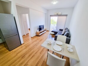 A compact living space with a kitchenette, a dining area, a sofa, and a TV. - Springfield Park Apartment (Larnaca)