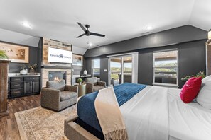Une chambre à coucher avec un lit, une cheminée, un ventilateur de plafond et une vue par la fenêtre.