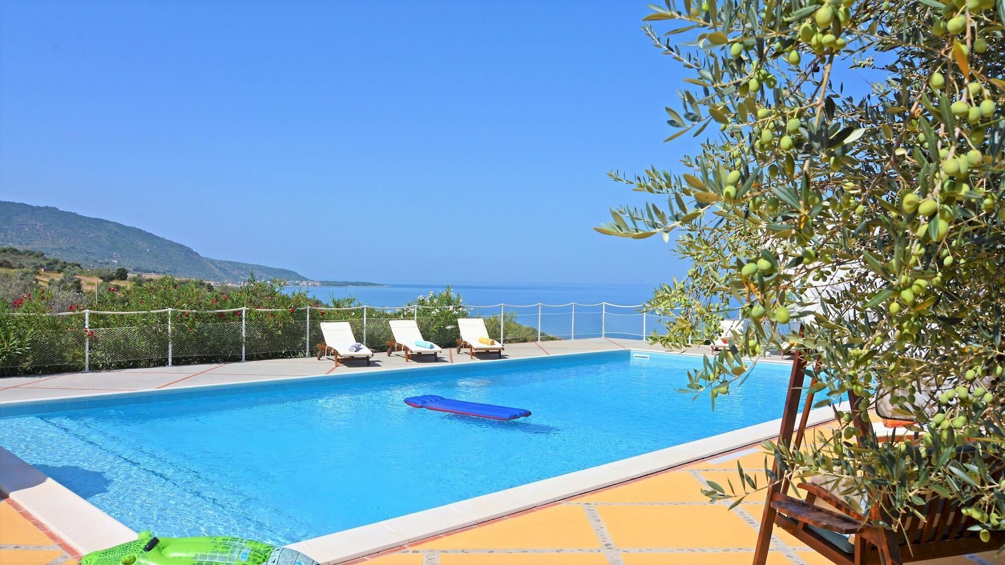 A swimming pool with lounge chairs and a view of the sea.
