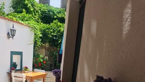 A patio with a table and chairs, a bicycle, and potted plants. - Adadaki Evimiz Bozcaada (Bozcaada)