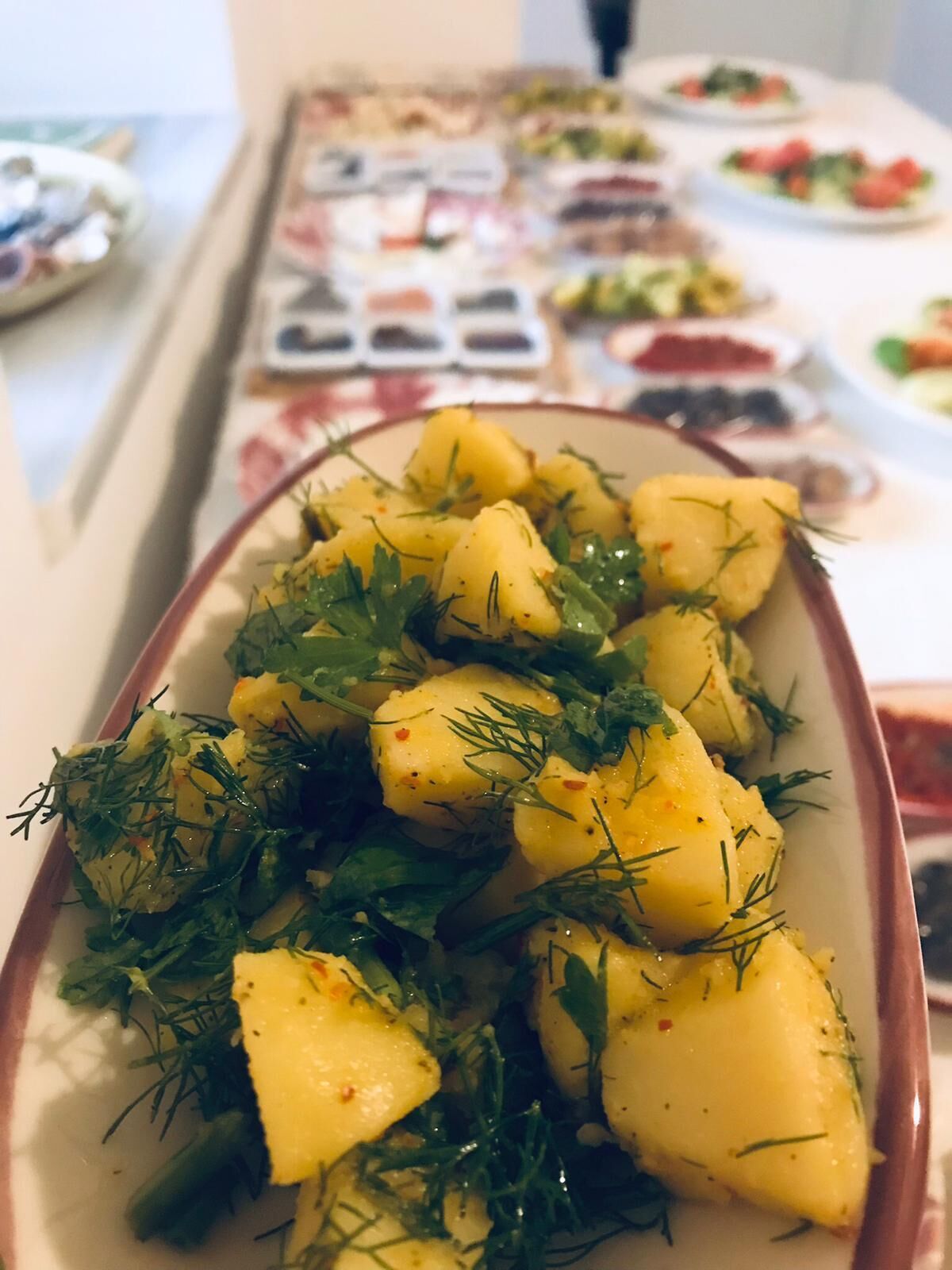 Una mesa con varios platos, incluyendo una ensalada de patatas adornada con hierbas.