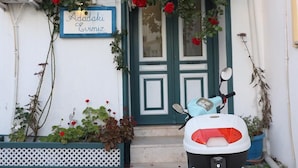 A scooter parked in front of a building with a sign reading "Adadaki Evimiz". - Adadaki Evimiz Bozcaada (Bozcaada)
