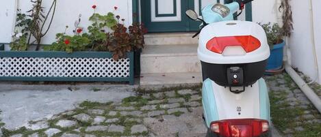 A scooter parked in front of a building with a sign reading "Adadaki Evimiz".