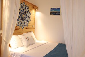 A bedroom with a wooden headboard, a bed with white bedding and decorative pillows, and a framed painting on the wall. - Adadaki Evimiz Bozcaada (Bozcaada)