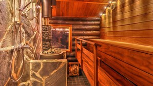 Een sauna met houten wanden, een stenen bank en een open haard van natuursteen.