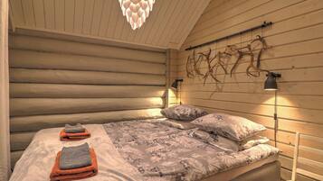 Un dormitorio de estilo cabaña de troncos con una cama, dos lámparas de noche y una lámpara de pared original.
