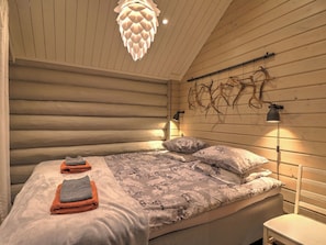 A log cabin-style bedroom with a bed, two bedside lamps, and a unique wall-mounted light fixture.