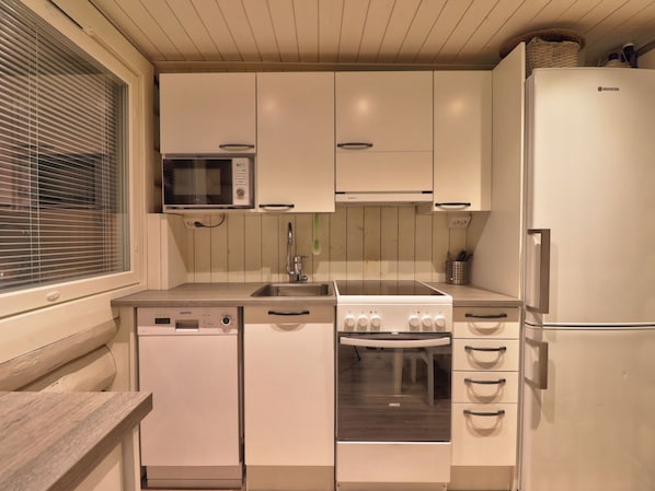 A compact kitchen with a microwave, dishwasher, stove, and refrigerator.