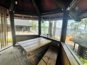 A wooden bench with a view of a lake and a wooden cabin in the background.