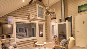 Een knus houten huisje interieur met een open haard, een televisie en een comfortabele zithoek.