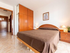A bedroom with a bed, wooden wardrobe, and a painting on the wall. - Living Park by Interhome (Salou)