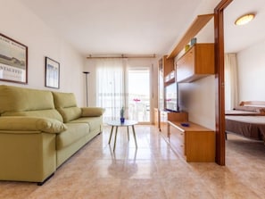 A living room with a sofa, a TV, and a bed in a hotel room. - Living Park by Interhome (Salou)