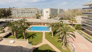 Un hotel con piscina circondato da palme, diversi piani e cielo sereno.