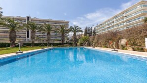 Una piscina circondata da palme e un edificio alberghiero a più piani.