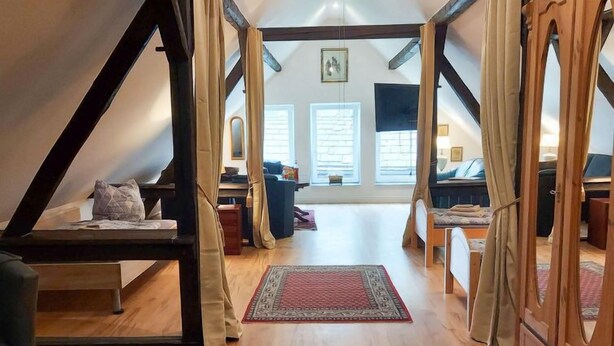 A spacious loft bedroom with a high ceiling, wooden beams, and a large window. - Lounge an der Kirche by Interhome (Hehlen)