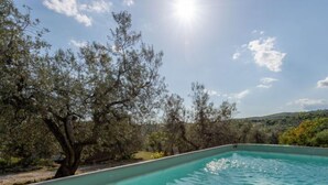 A swimming pool with clear water, surrounded by trees and a hilly landscape. - Fonte al Tesoro by Interhome (Sassofortino)