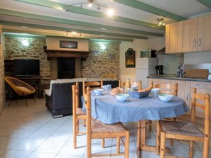 A cozy dining area with a stone fireplace, wooden chairs, and a table set for a meal.