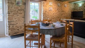 A stone-walled room with a dining table set for four, surrounded by wooden chairs. - Vacation home Ty Coz by Interhome (Pleurtuit)