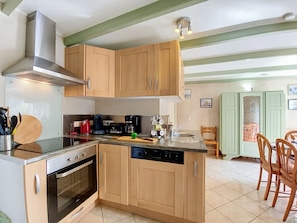 A compact kitchen with wooden cabinets, a built-in oven, and a dishwasher. - Vacation home Ty Coz by Interhome (Pleurtuit)